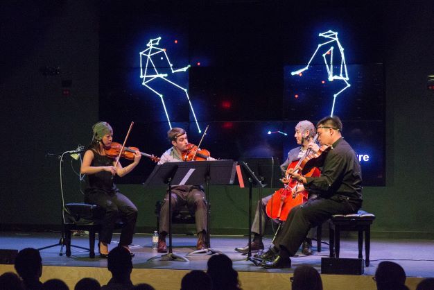 Three musicians and one participant are on stage during a Live Lab performance
